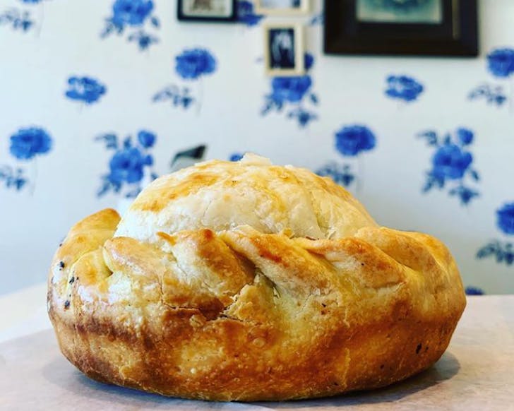A delicious-looking pie on a table in front of white wallpaper with blue roses. 