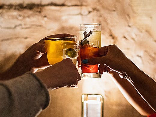 People hold cocktails aloft at Panacea.