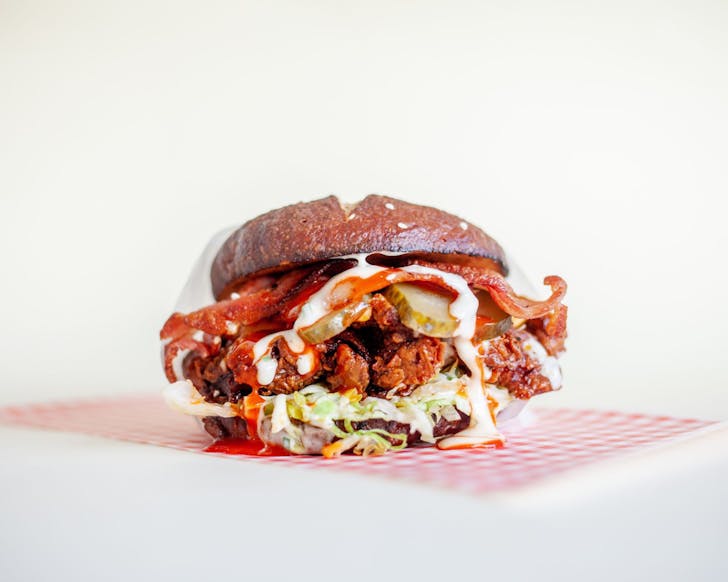 A small burger stuffed with fired chicken, pickles and sauce oozing out from Parade, one of the best Ponsonby restaurants  