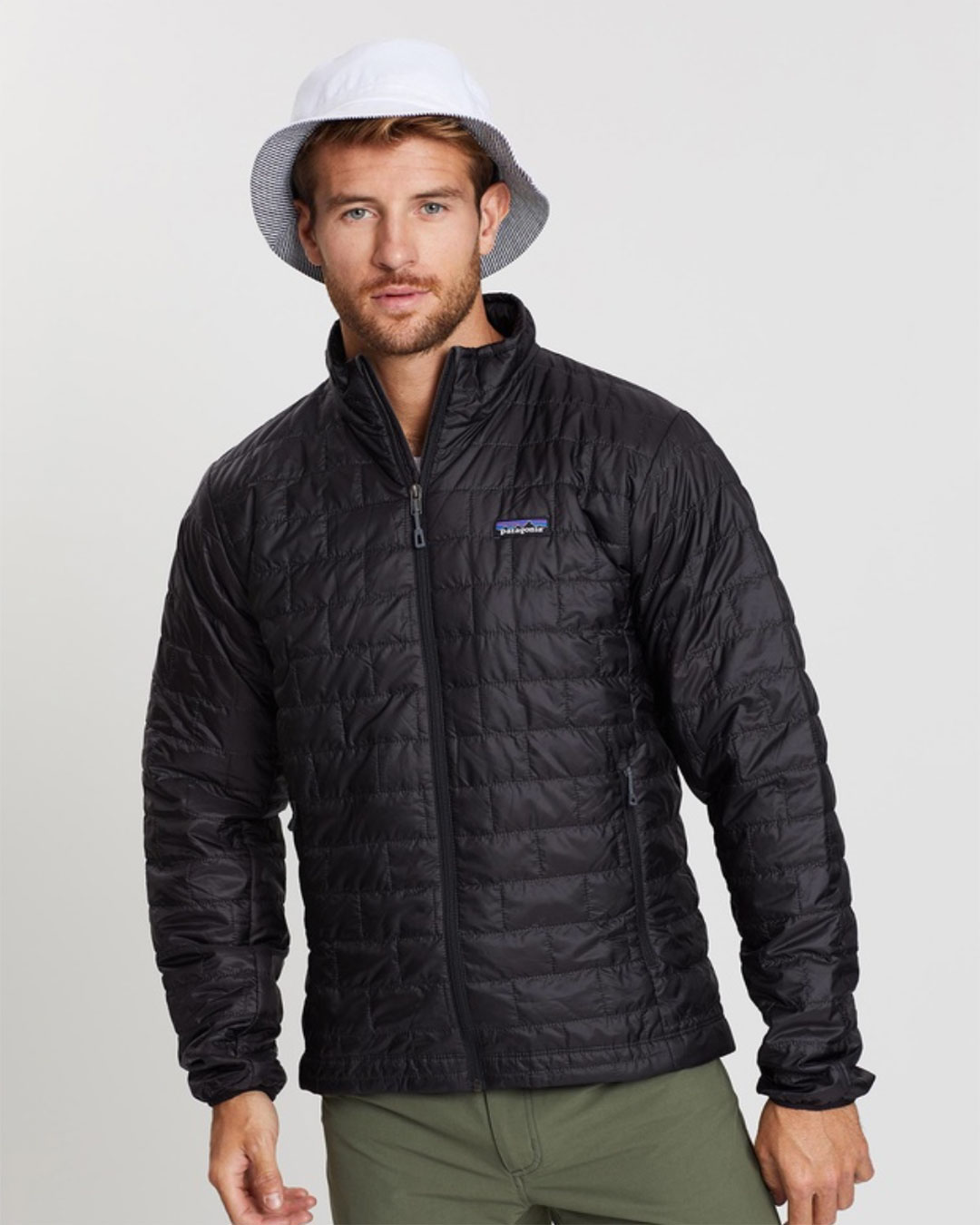 A man wearing a black Patagonia puff jacket with a white bucket hat.