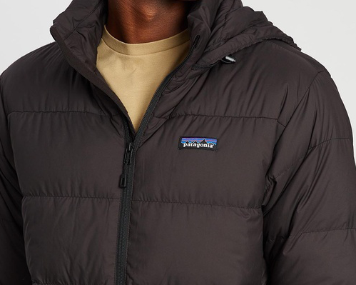 A person wearing a black jacket with a yellow t shirt, one of the best men's puffer jackets. 