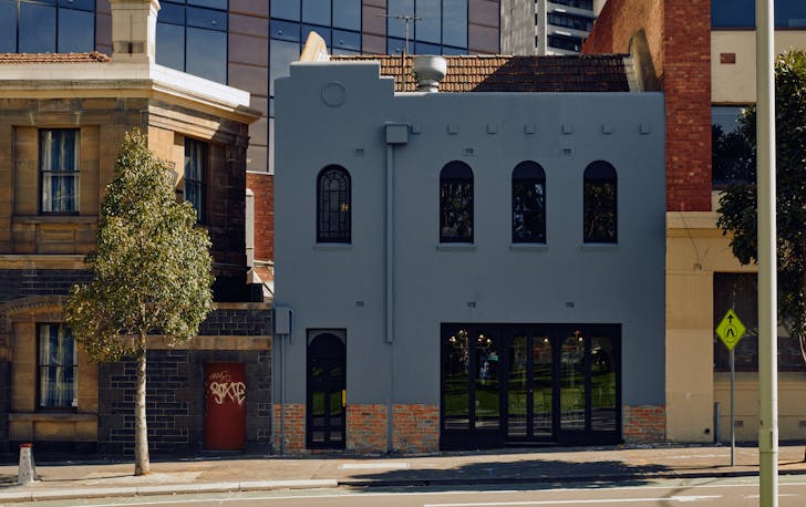The front exterior of Patsys, a blueish grey building with arched windows and glass door. 