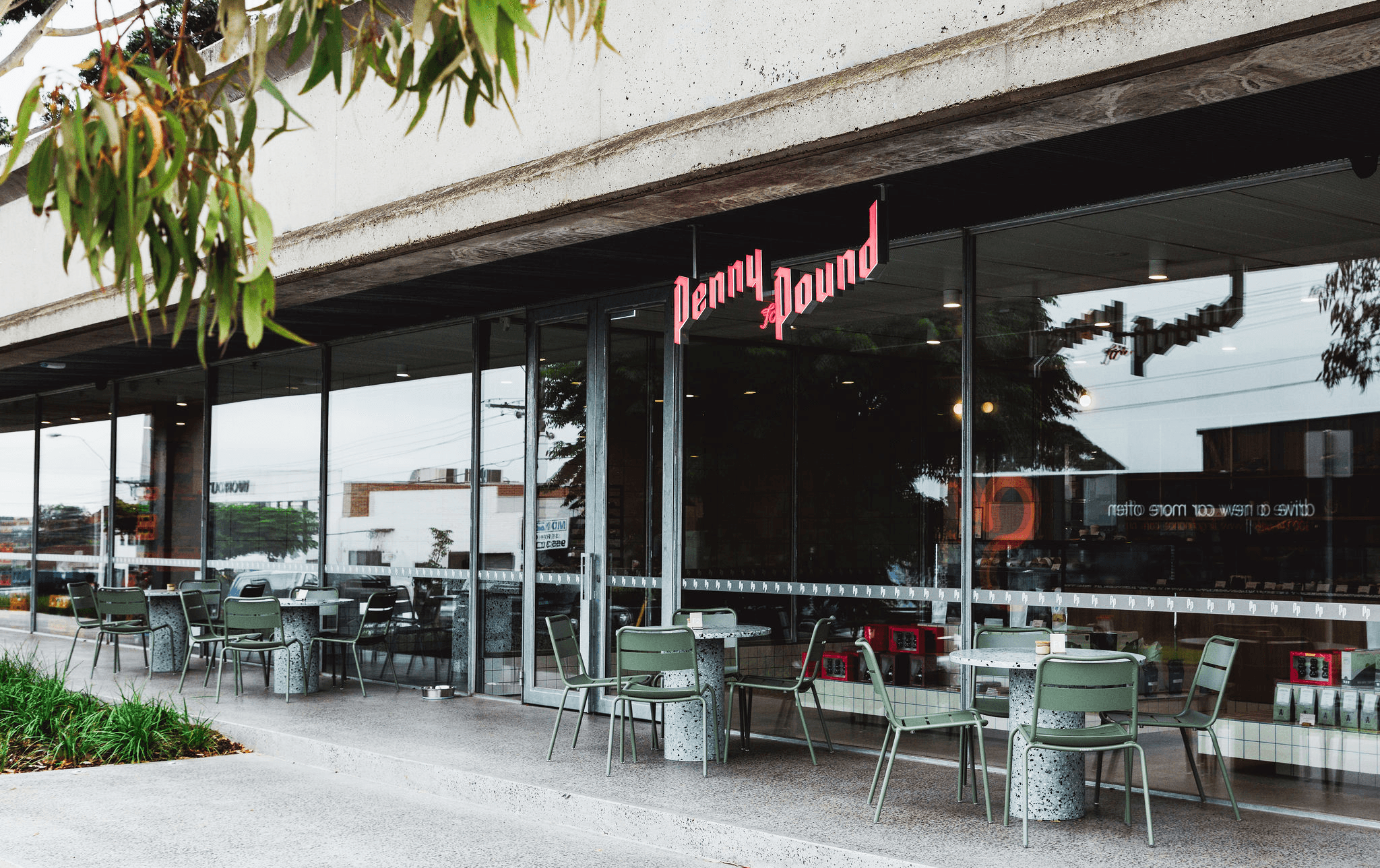 A cafe storefront with green tables and chairs. 