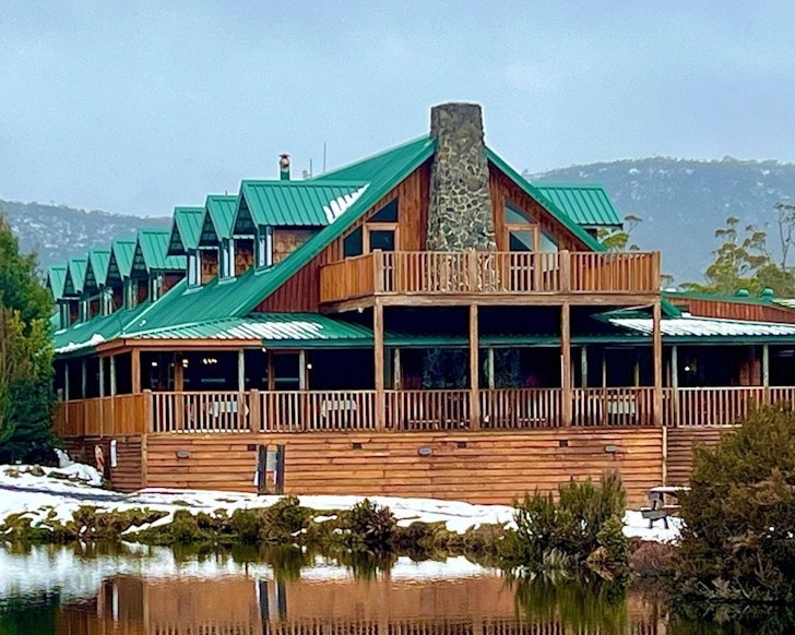 An exterior view of Peppers Cradle Mountain Lodge one of the best hotels in Tasmania with its green roof and mountains in the background