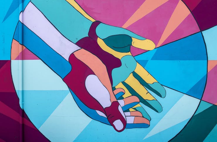 Mural of two hands brightly painted in blues, pinks and greens