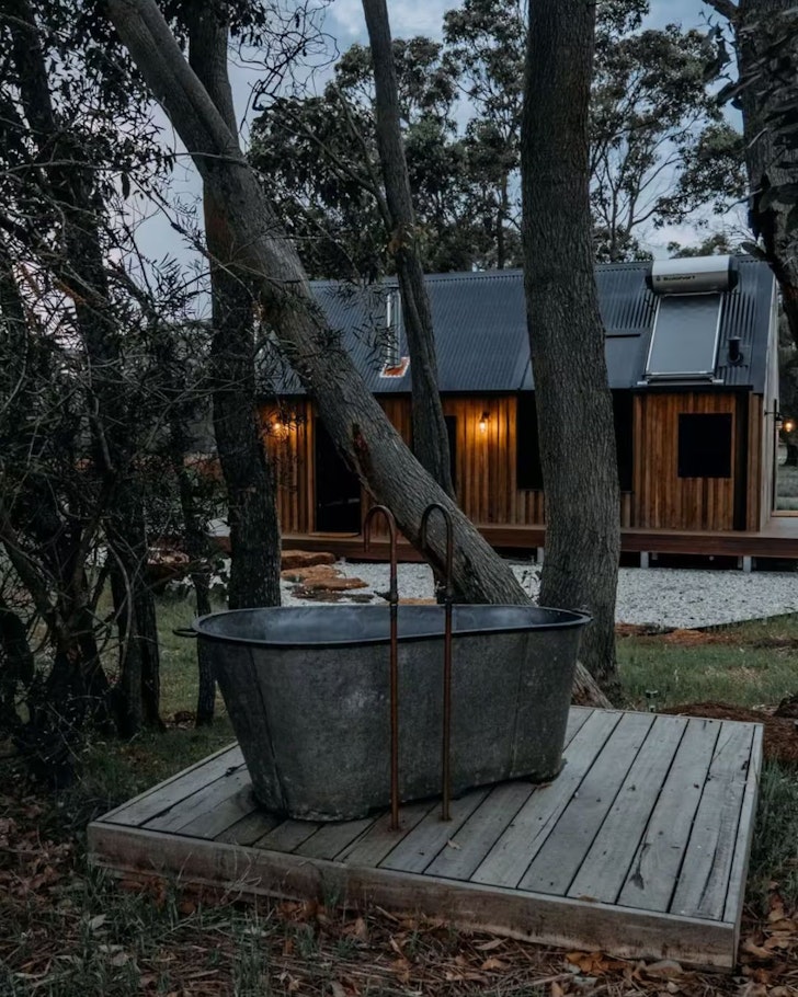 A view of the outdoor bath with the cabin in the background at Petit Eco Cabin Airbnb one of the best romantic getaways in Australia