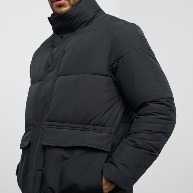 A person wearing one of the best men's puffer jackets in black. 