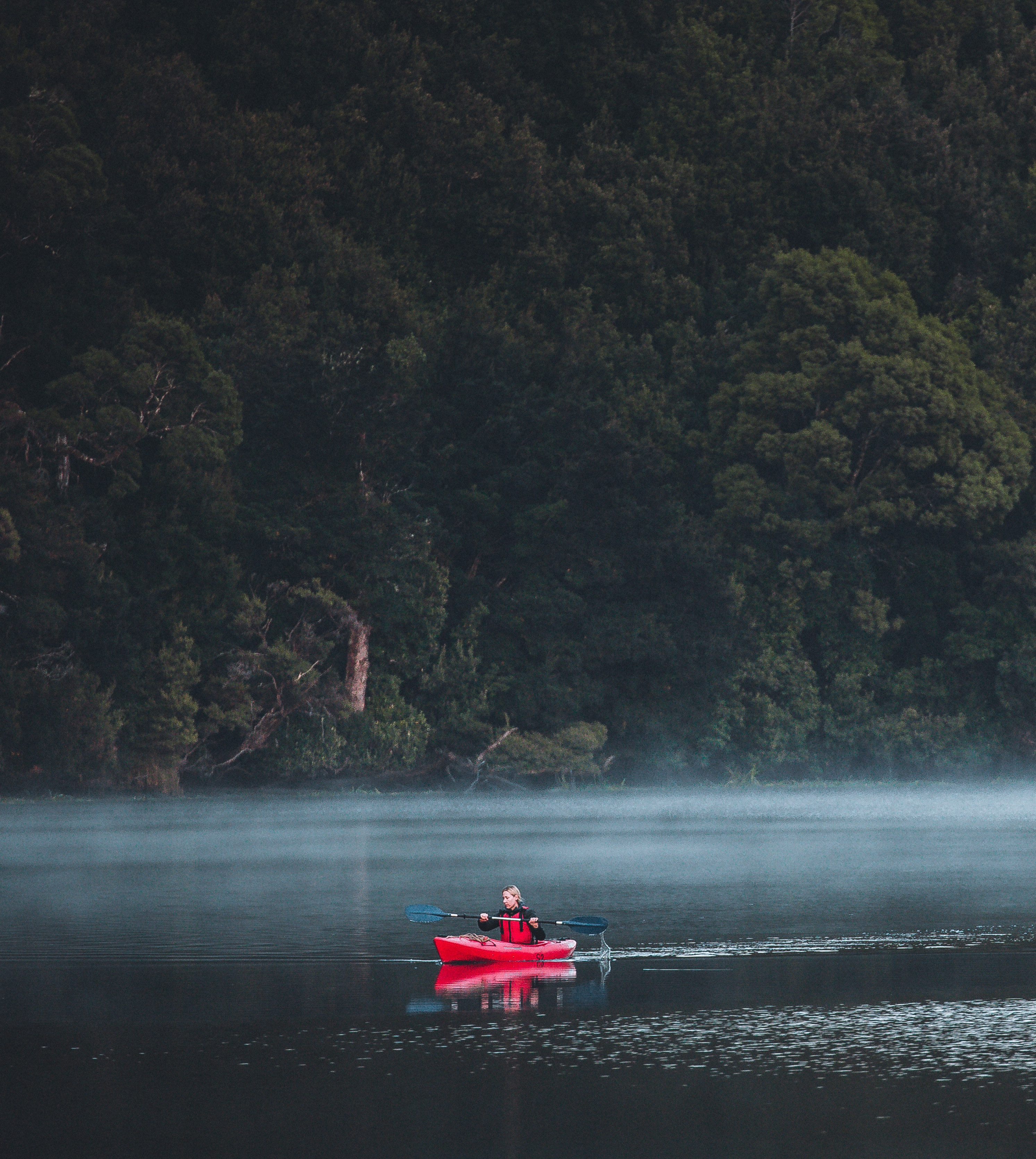 A red kayak floats down the Pieman River in Tasmania.