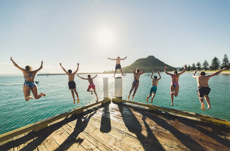 People leaping off the pier at Pilot Bay in Mount Maunganui.
