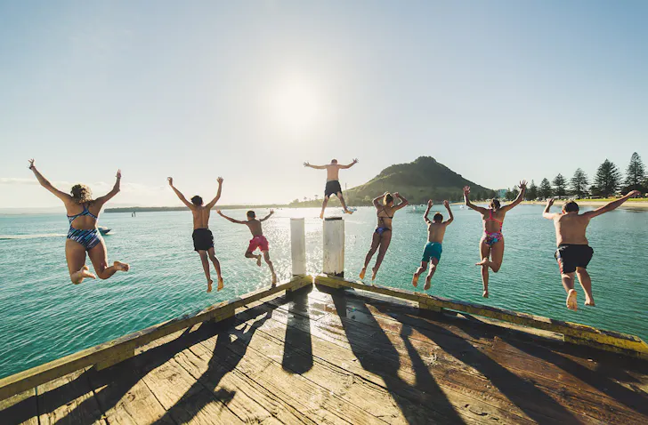 People leaping off the pier at Pilot Bay in Mount Maunganui.