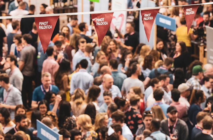 a crowd of people at the pinot event under a red 'pinot palooza' banner