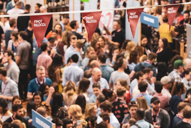 a crowd of people at the pinot event under a red 'pinot palooza' banner
