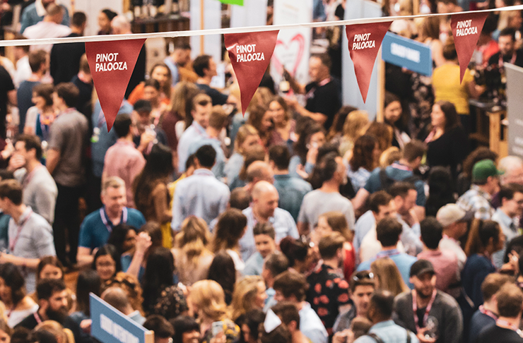 a crowd of people at the pinot event under a red 'pinot palooza' banner