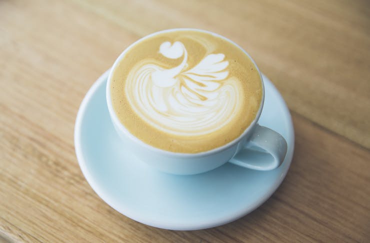 A coffee in a blue mug with latte art of a swan