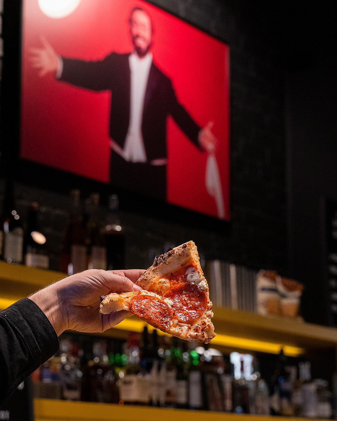 Someone holds a delicious pizza aloft at Dunedin's Pizza Bar.