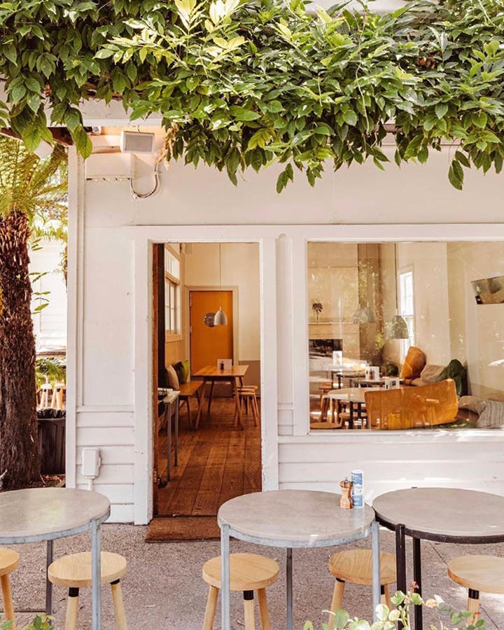A white shopfront with trees and furniture, a best lorne restaurant option. 
