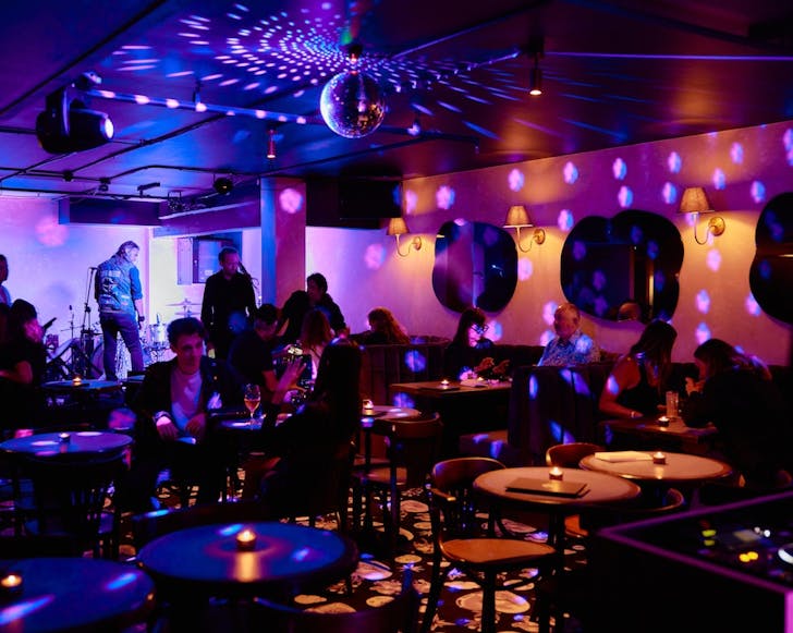Indoor wide shot of Pleasure Club with disco lights and a moody atmosphere.
