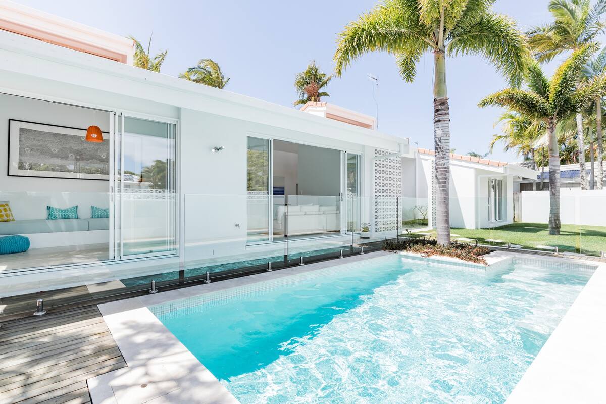 a pool in front of a white house under a blue sky