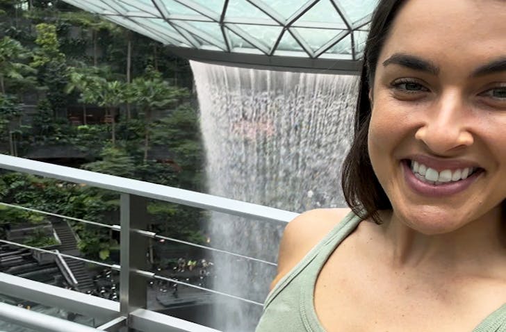 Woman takes a selfie in front of the HSBC Rain Vortex in Jewel Changi Airport