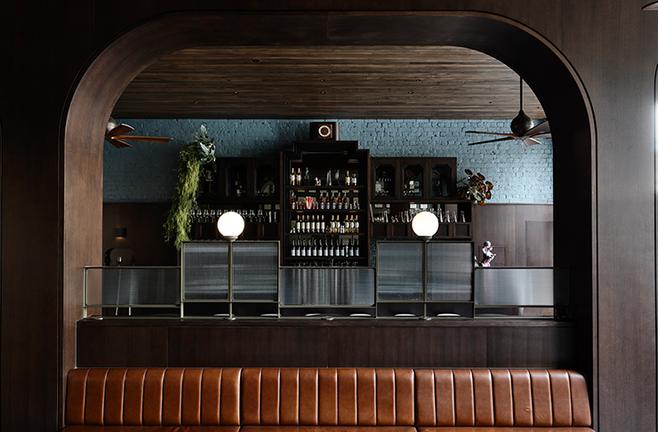 A leather booth sits in front of a bar at one of Melbourne's best restaurants, Poodle.