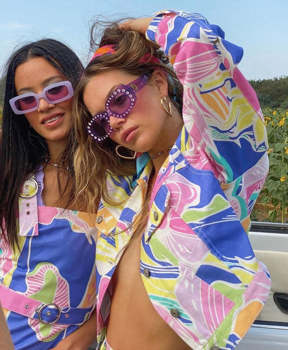 Two women rock bedazzled shades and printed outfits. 