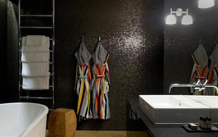 A black-tiled bathroom of a top winery accommodation Victoria contender. 