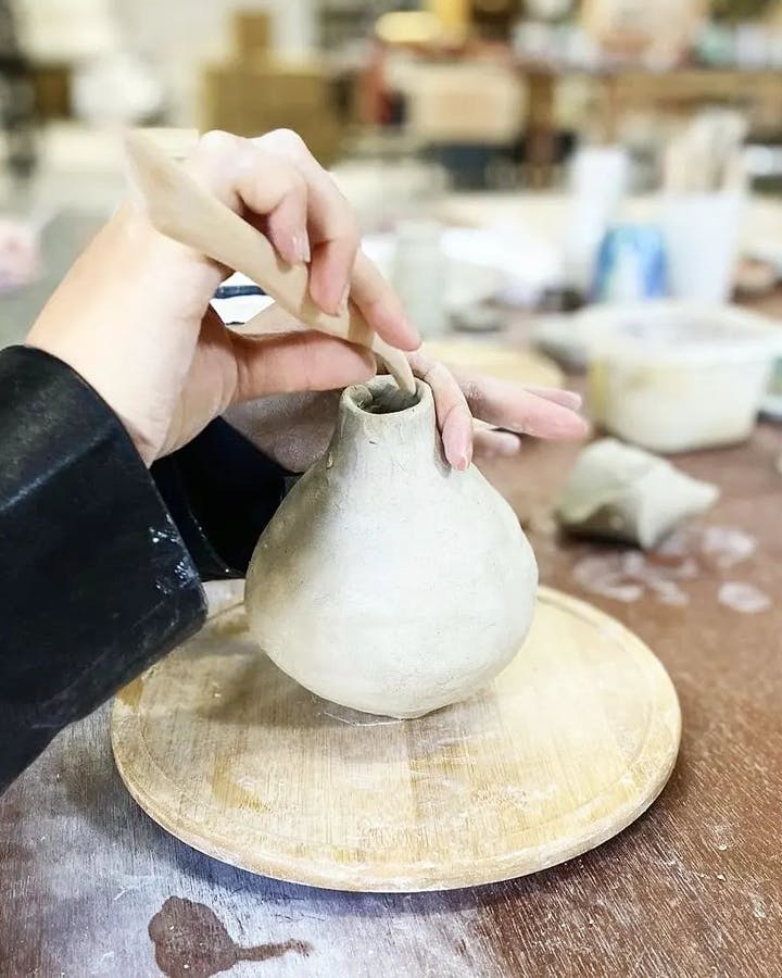 A person at a best pottery class Melbourne carving out with a tool. 