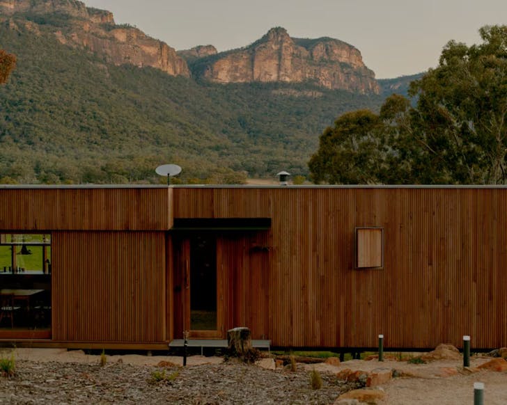 An exterior view of Practice Ground cabin NSW with the sandstone escarpment behind