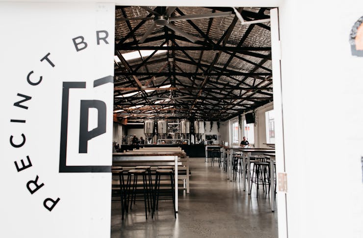 the white doors of precinct brewing half, ajar, displaying the industrial interior of a brewpub