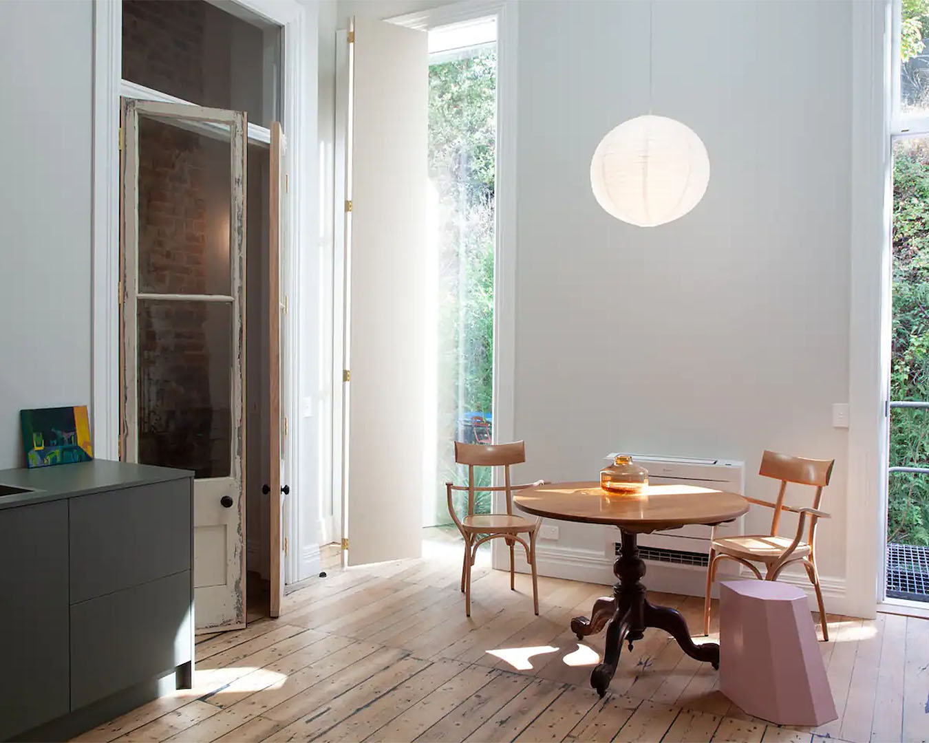 A wooden-floored apartment with large windows overlooking the garden.