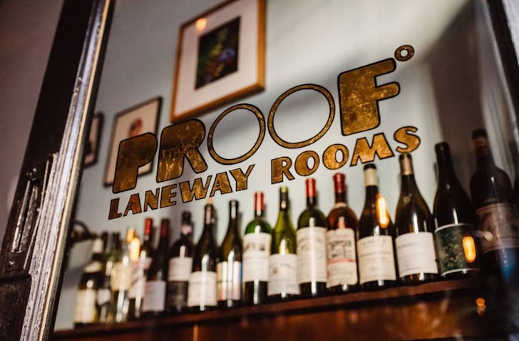 Glass-fronted wine room at Proof, gold signage, curated bottles