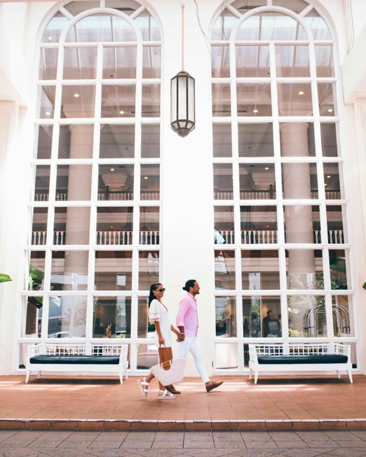 A couple walks past the huge windows at the Pullman Cairns International hotel