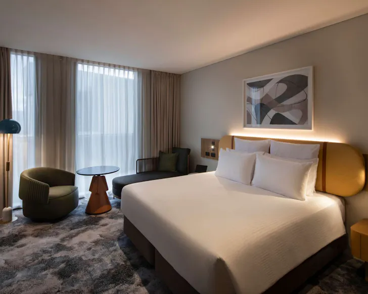 A large hotel bed and modern furnishing at the Pullman Sydney Penrith.