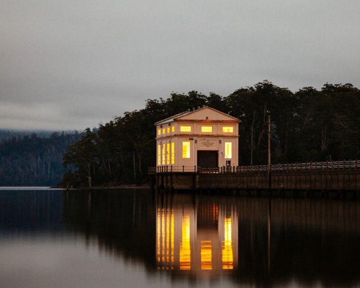 A view of Pumphouse Point lakehouse surrounded by water at dusk in Tasmania