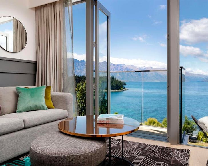 A sumptuous living room looks out upon the lake at QT Queenstown.