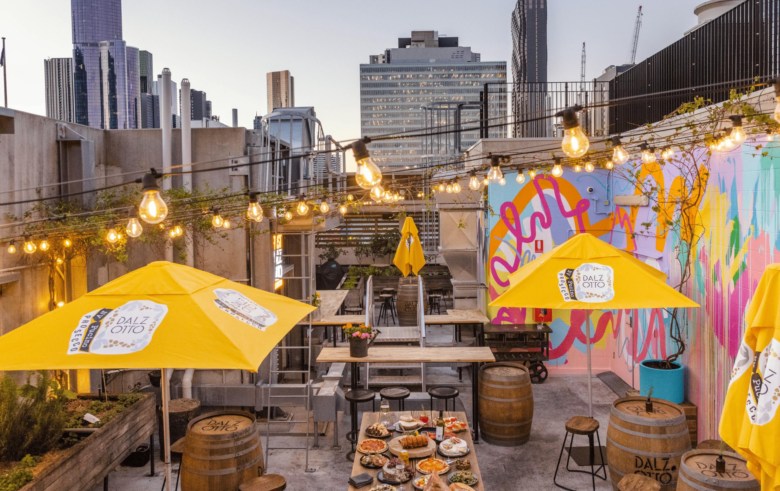 A rooftop bar with fairy lights and yellow umbrellas