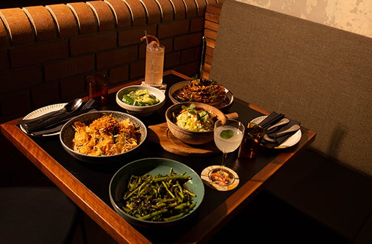 A table of dishes and cocktails inside a dim lit restaurant