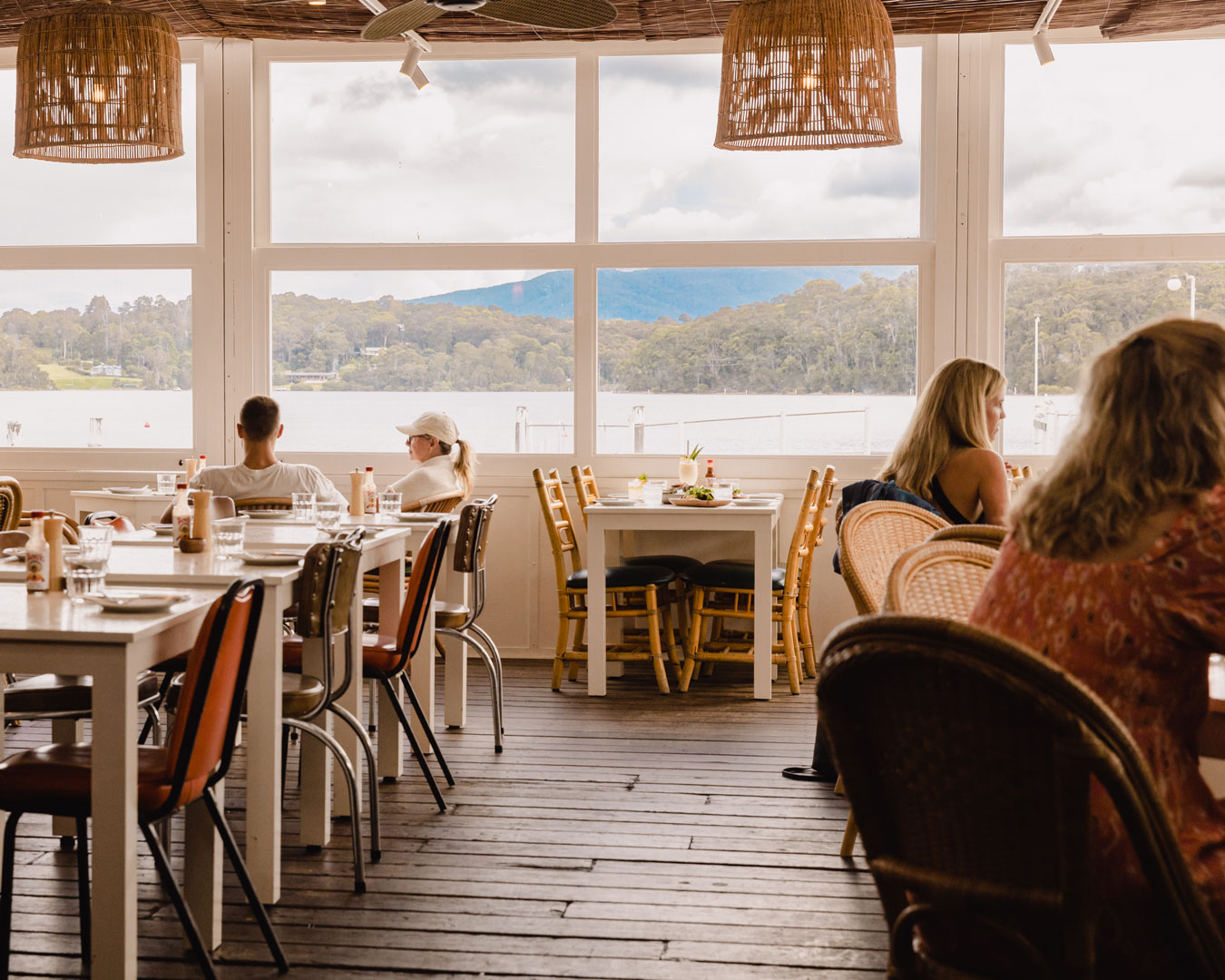 People in restaurant overlooking water and mountains