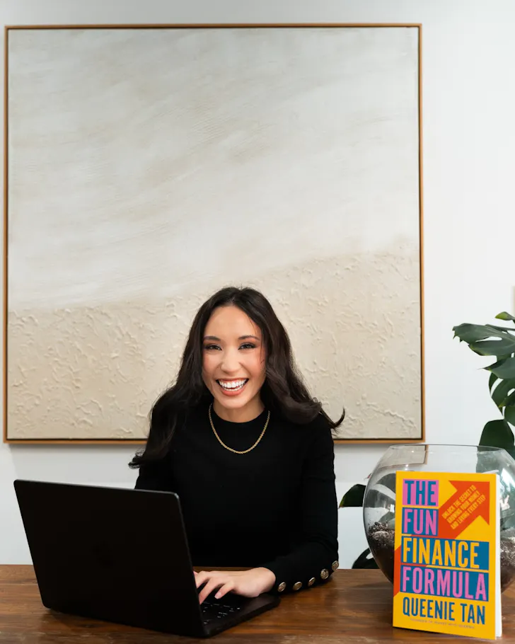 A woman smiles alongside a book and a laptop.