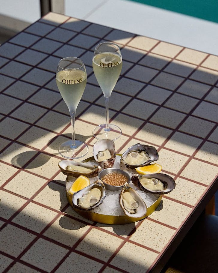 A pair of champagne glasses and oysters on a grid table.