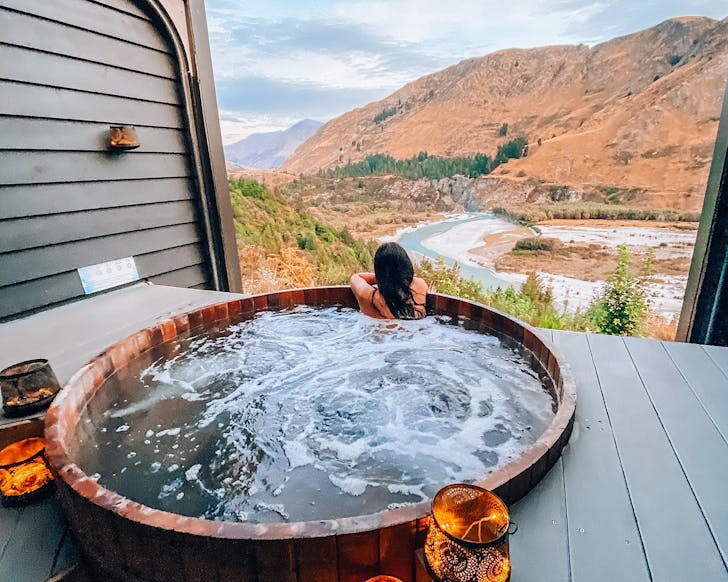 A woman soaks up a stunning nature view while in an onsen hot pool in Queenstown.