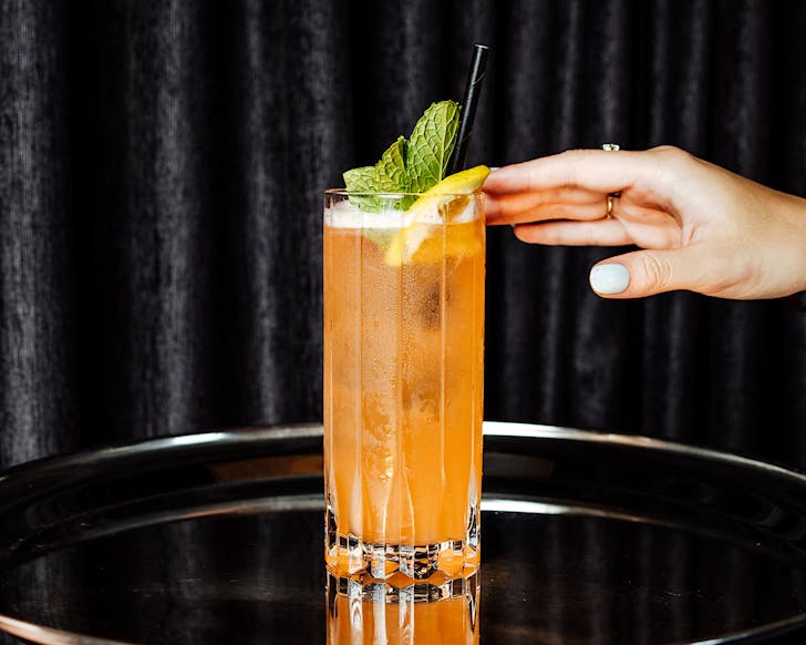 Someone with a white manicure reaches for a tropical cocktail. 