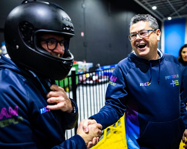 A rider and power play owner shake hands post-race