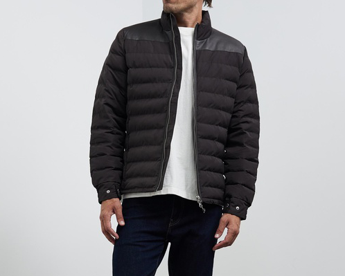  A person in a white t-shrt and a black quilted jacket, one of the best men's puffer jackets. 
