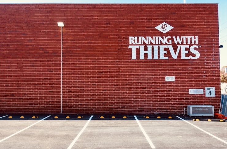 Red brick wall with Running With Thieves logo
