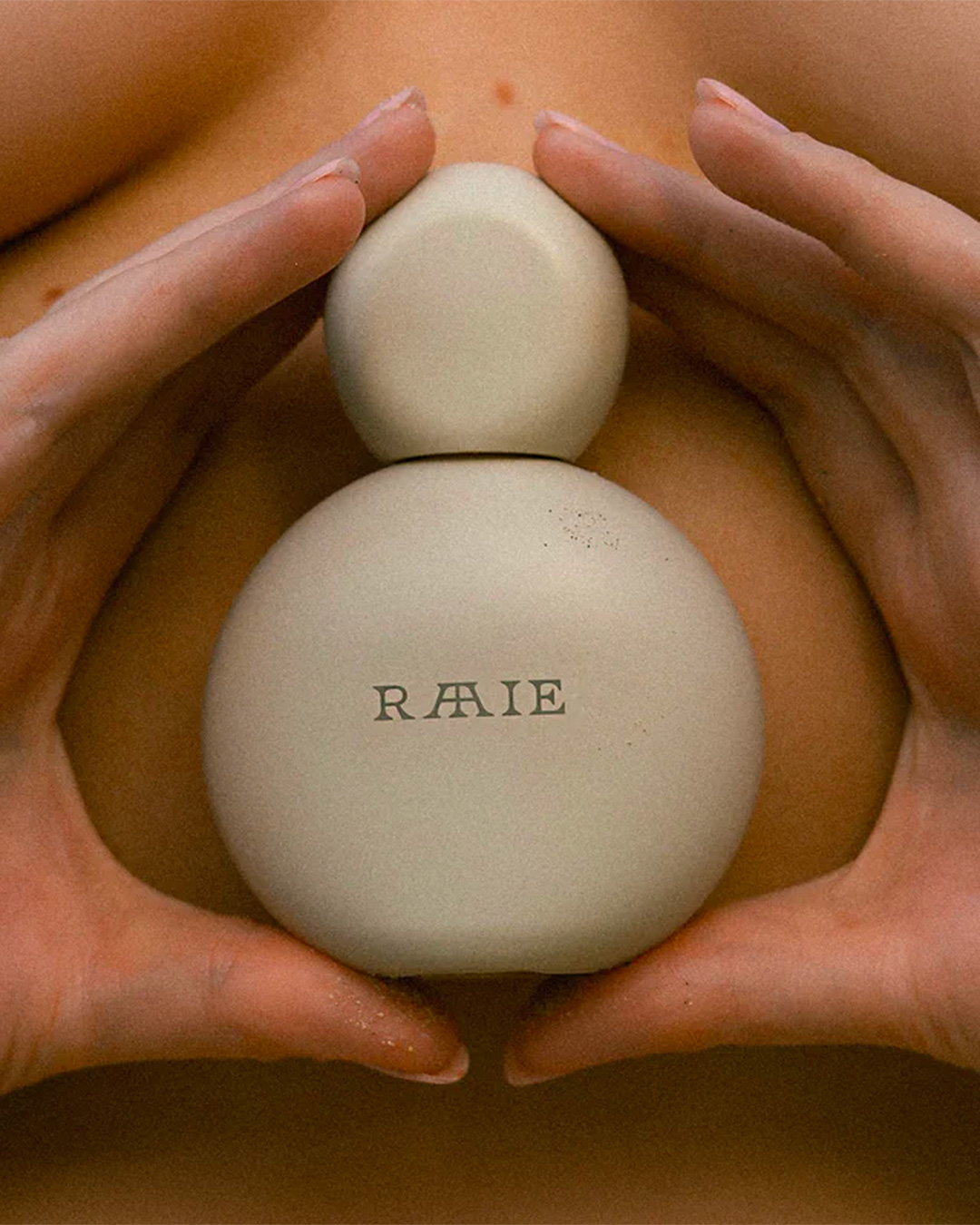 Someone holds a bottle of Raaie Skincare.