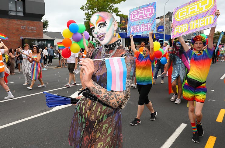 A drag queen poses fabulously while surrounded by rainbow flags on Ponsonby Road.