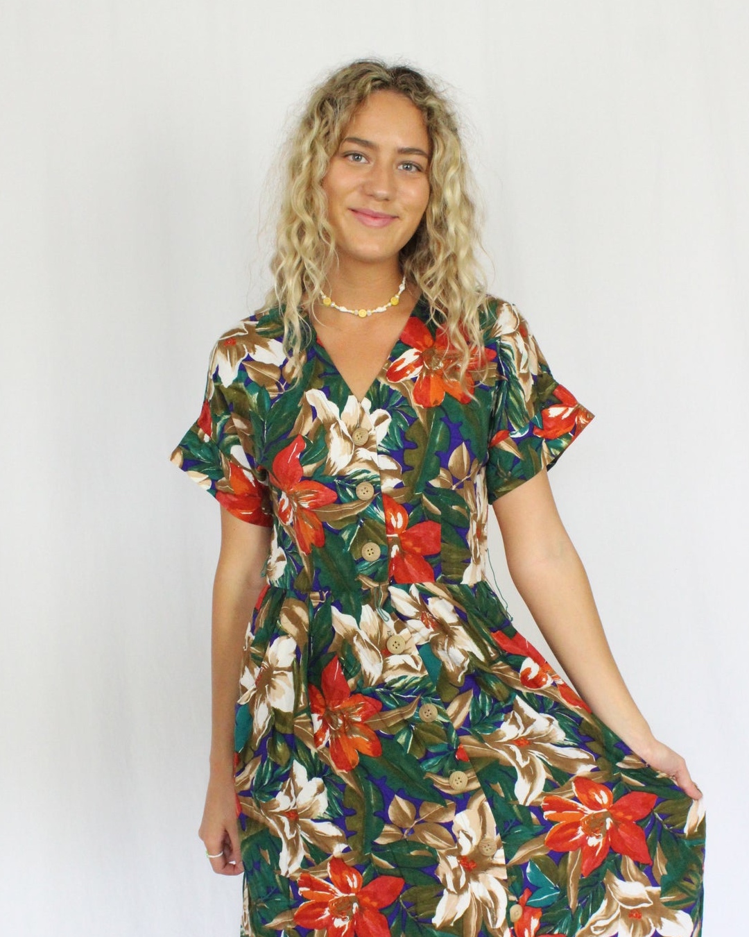 A woman wears a dark green vintage American dress in a floral print. 