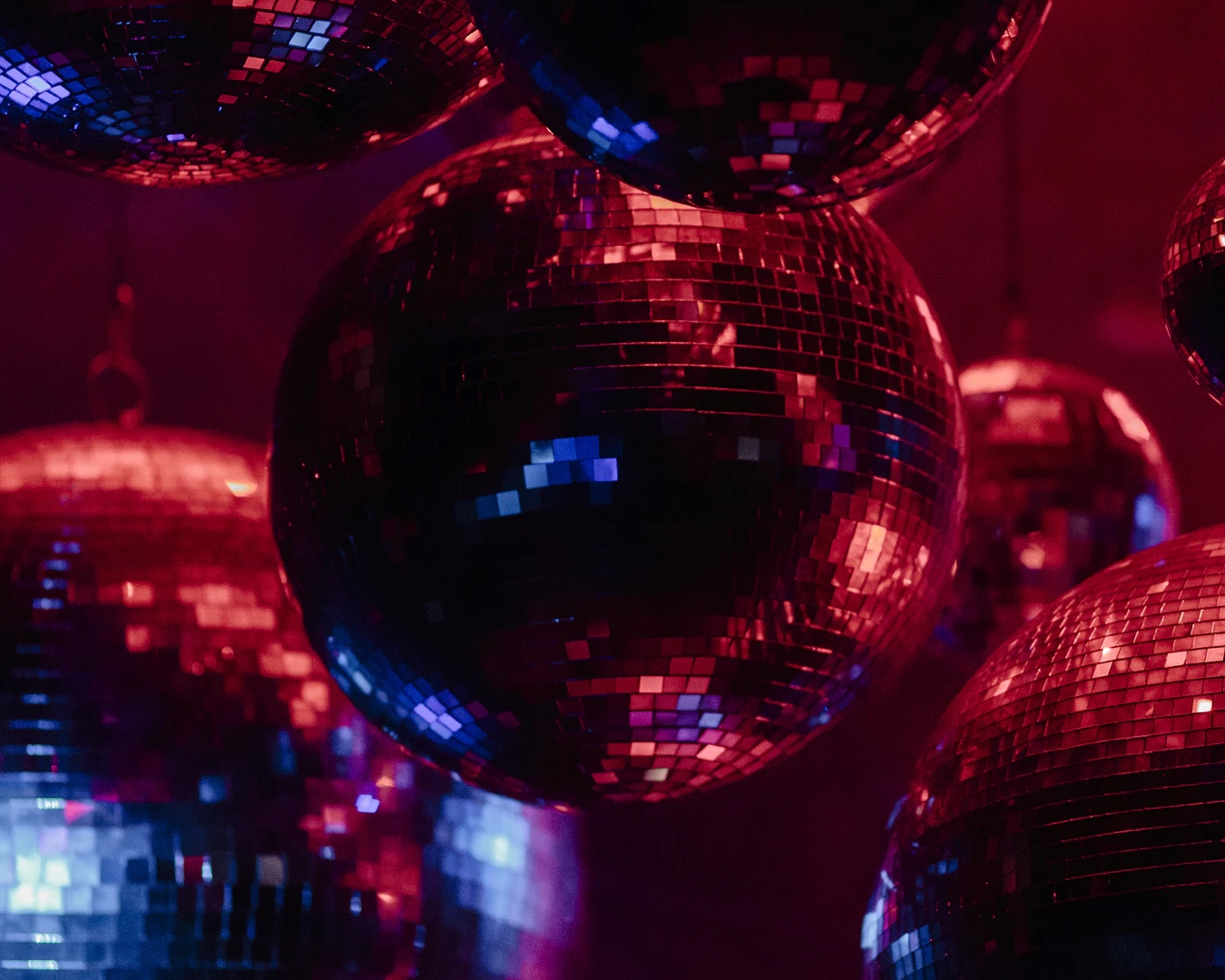 A collection of disco balls lit in red and purple lights. 
