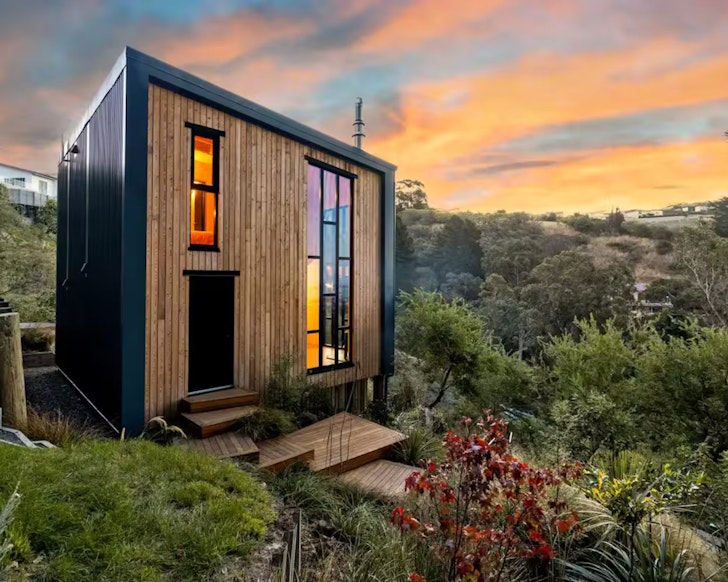 The timber clad exterior of Redcliffs Treehouse surrounded by trees one of the best romantic stays in New Zealand